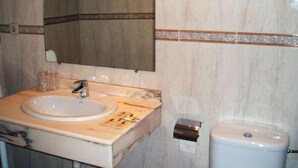 Un bany amb un lavabo de marbre, un mirall i un vàter.