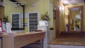 Tauleller de recepció amb un monitor d'ordinador, una planta i una escala que condueix a una planta superior.