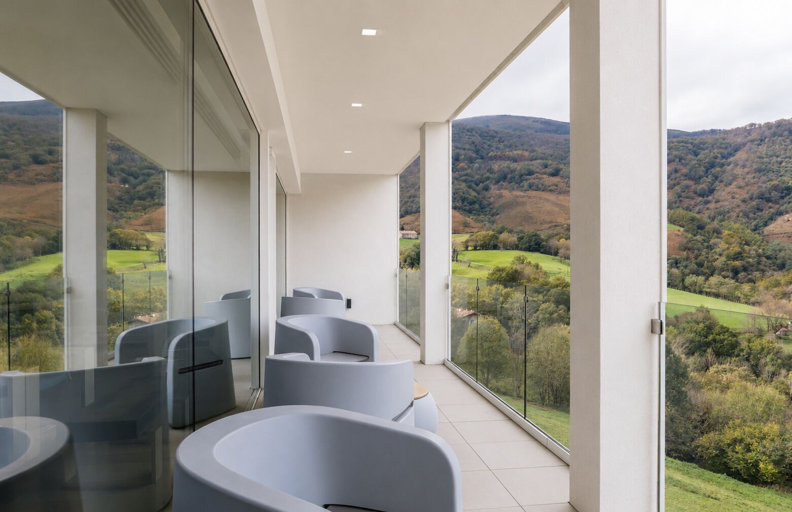 Un balcon avec des chaises modernes et une vue sur un paysage vallonné.