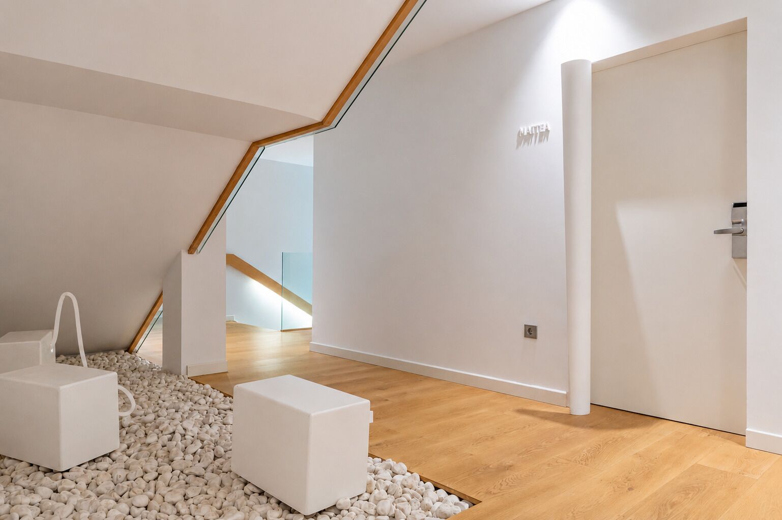 Un interior moderno con una escalera de madera, una puerta blanca y suelo de piedrecitas.