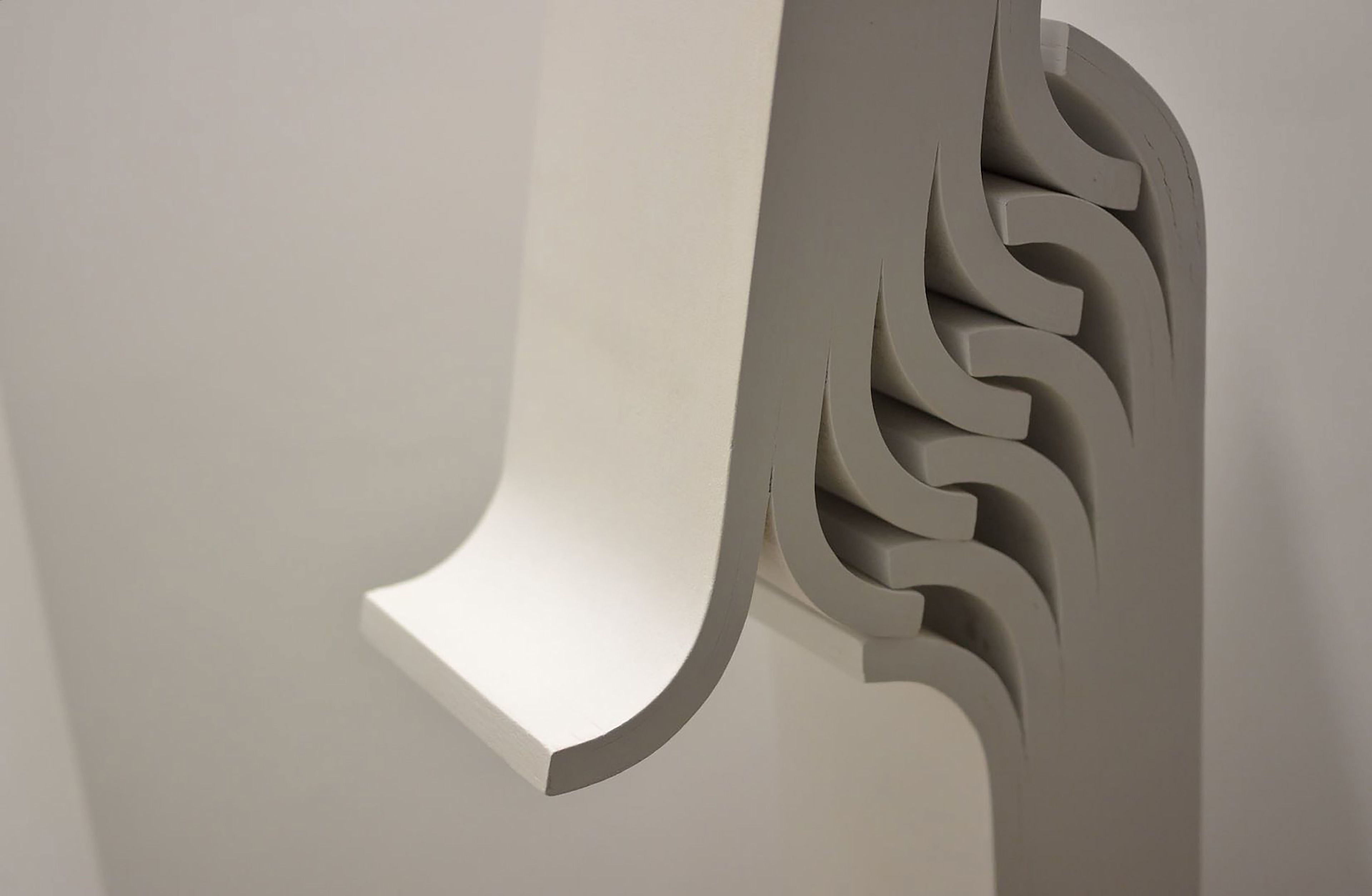 Um detalhe próximo de uma estrutura arquitetônica branca e curva, com um padrão decorativo ondulado.