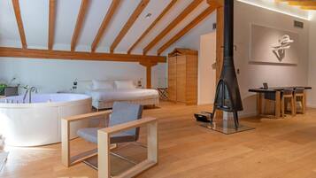 Un dormitorio moderno con una cama grande, techo de madera, un calentador negro y una pequeña mesa con sillas.