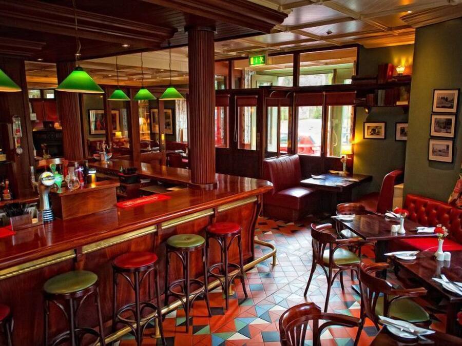 Eine Bar mit Sitzstühlen, einer Theke und einer Sitzgruppe mit Tischen und Sesseln.