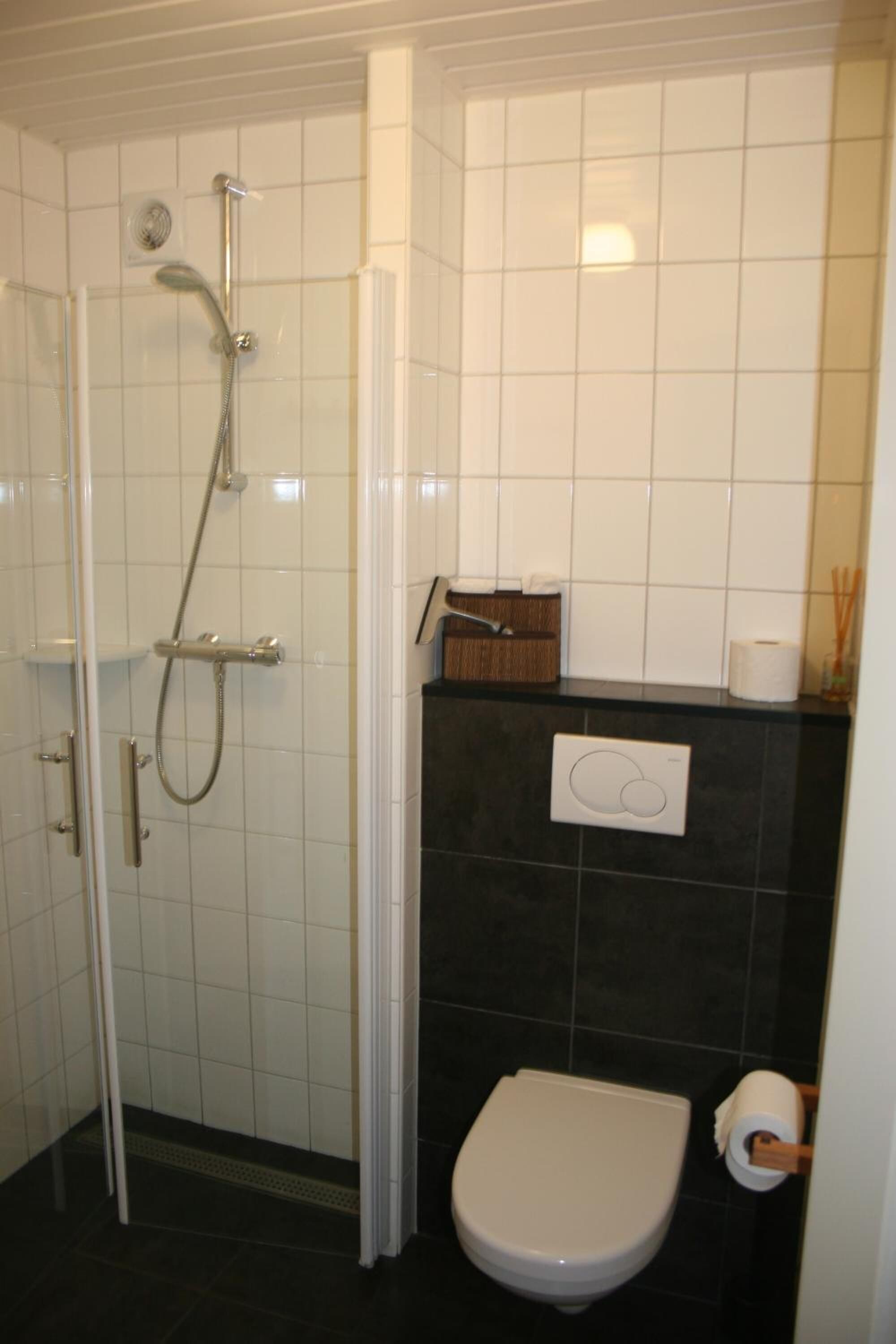 Un baño con ducha, inodoro y toallero.