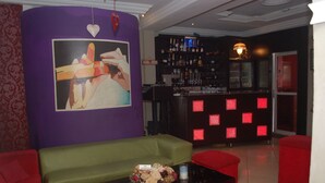 A bar area with a purple wall, a green sofa, and red chairs. - Dcove Hotel & Suites (Lagos)