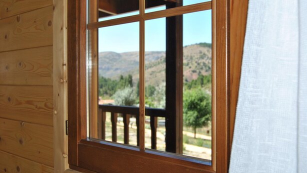 A wooden cabin with a window revealing a mountainous landscape. - Cabañas de Javalambre (Camarena de la Sierra)