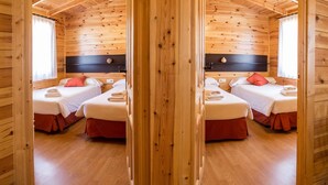 A mirrored view of a wooden cabin room with two beds, each with a red pillow and white bedding. - Cabañas de Javalambre (Camarena de la Sierra)