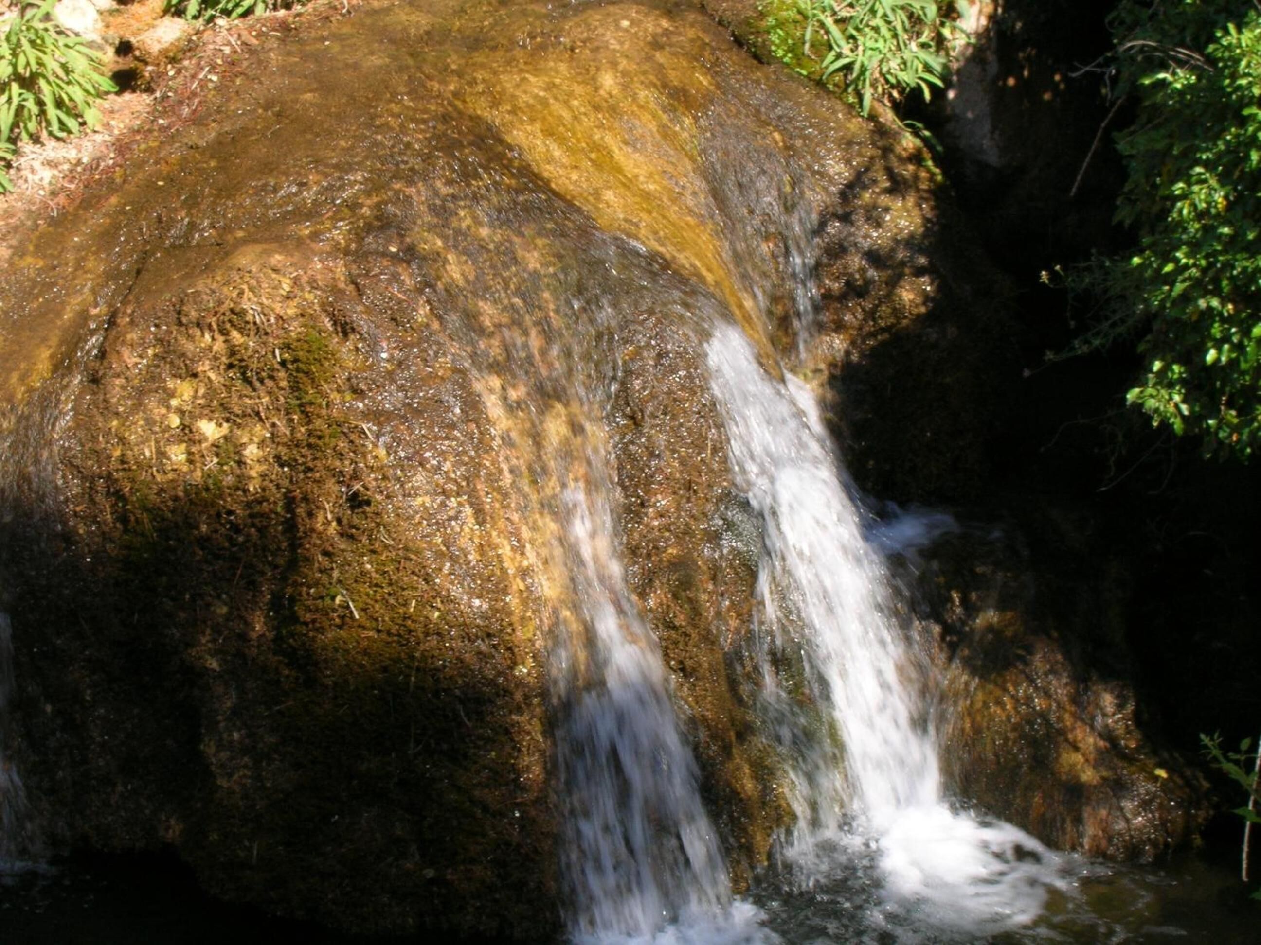Una formació rocosa natural amb una petita cascada.
