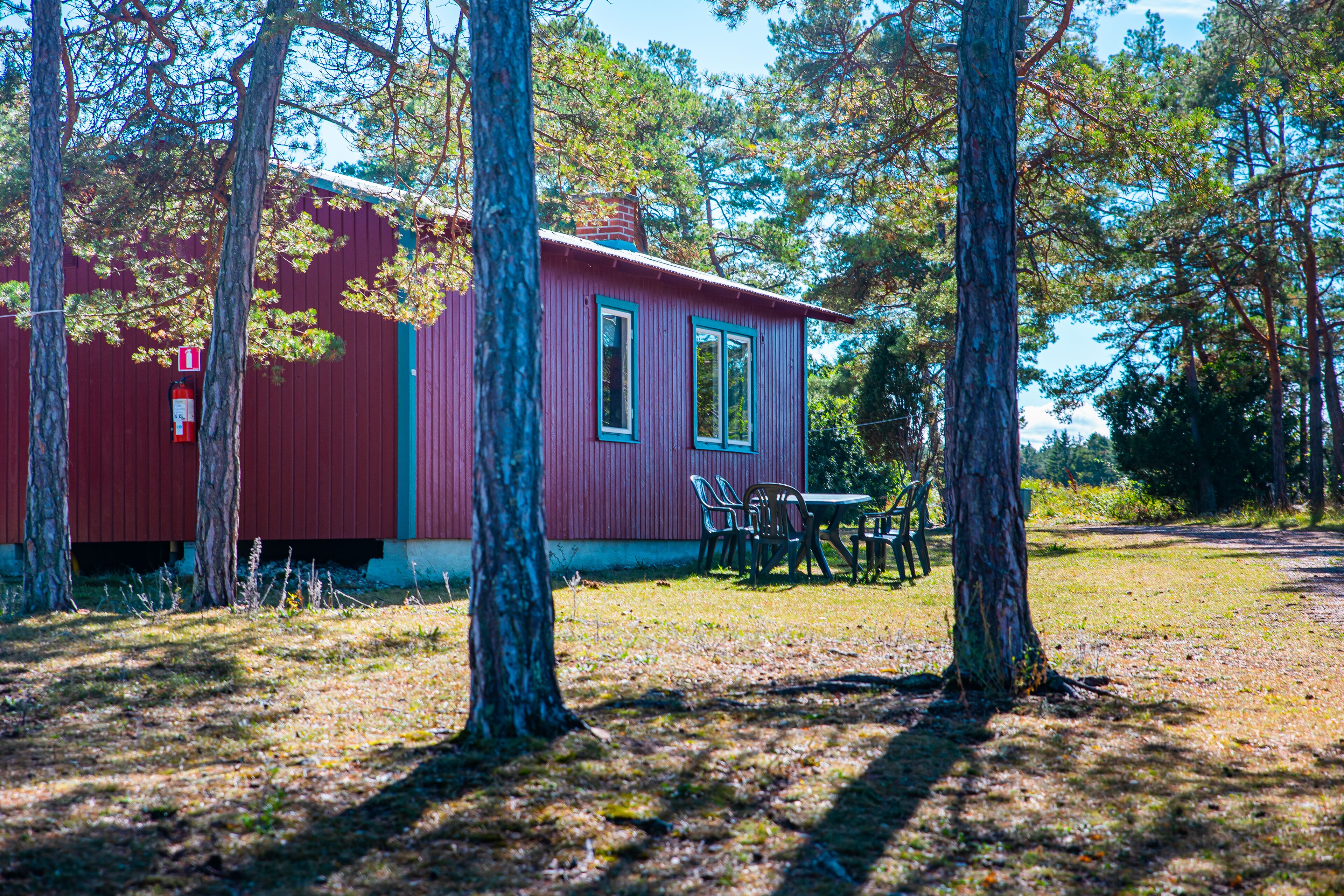 A red cabin with two windows and a table with chairs outside.