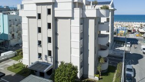 A multi-story building with balconies, a parking area, and a view of the beach and ocean. - Residenza Levante (Riccione)