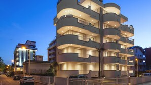 A multi-story building with balconies, a gated entrance, and a parking area. - Residenza Levante (Riccione)