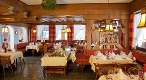 Un restaurante con interiores de madera, varias mesas y bancos.