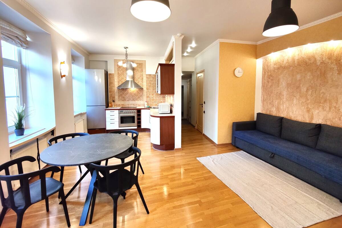 A modern kitchen with a central island, wooden flooring, and pendant lighting.