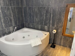 Un baño moderno con una bañera independiente, un cabezal de ducha de mano y un dispensador de papel higiénico.