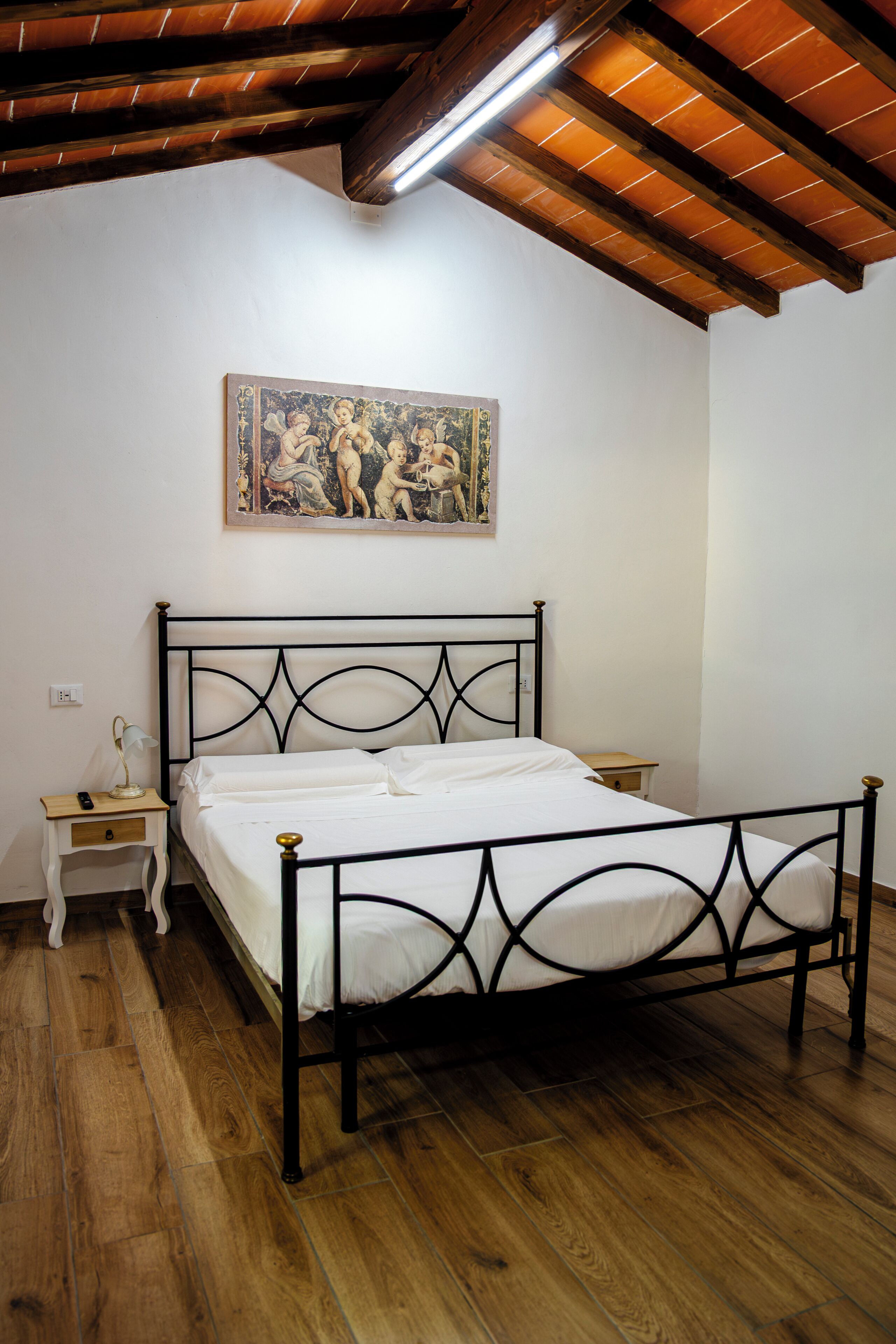 A bedroom with a bed, a nightstand, a lamp, and a painting on the wall.