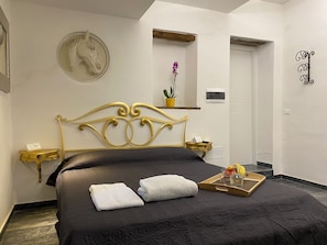 Un dormitorio con cama, un reloj de pared, una planta en maceta y una puerta.