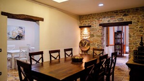 A dining area with a wooden table and chairs, a stone wall, and a painting on the wall. - Agriturismo il Casolare - Villa Vettori (Poppi)