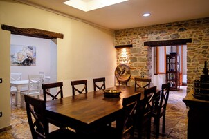 Un comedor con una mesa y sillas de madera, una pared de piedra y un cuadro en la pared.