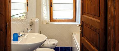 A bathroom with a wooden ceiling, a window, a sink, a toilet, and a bathtub.
