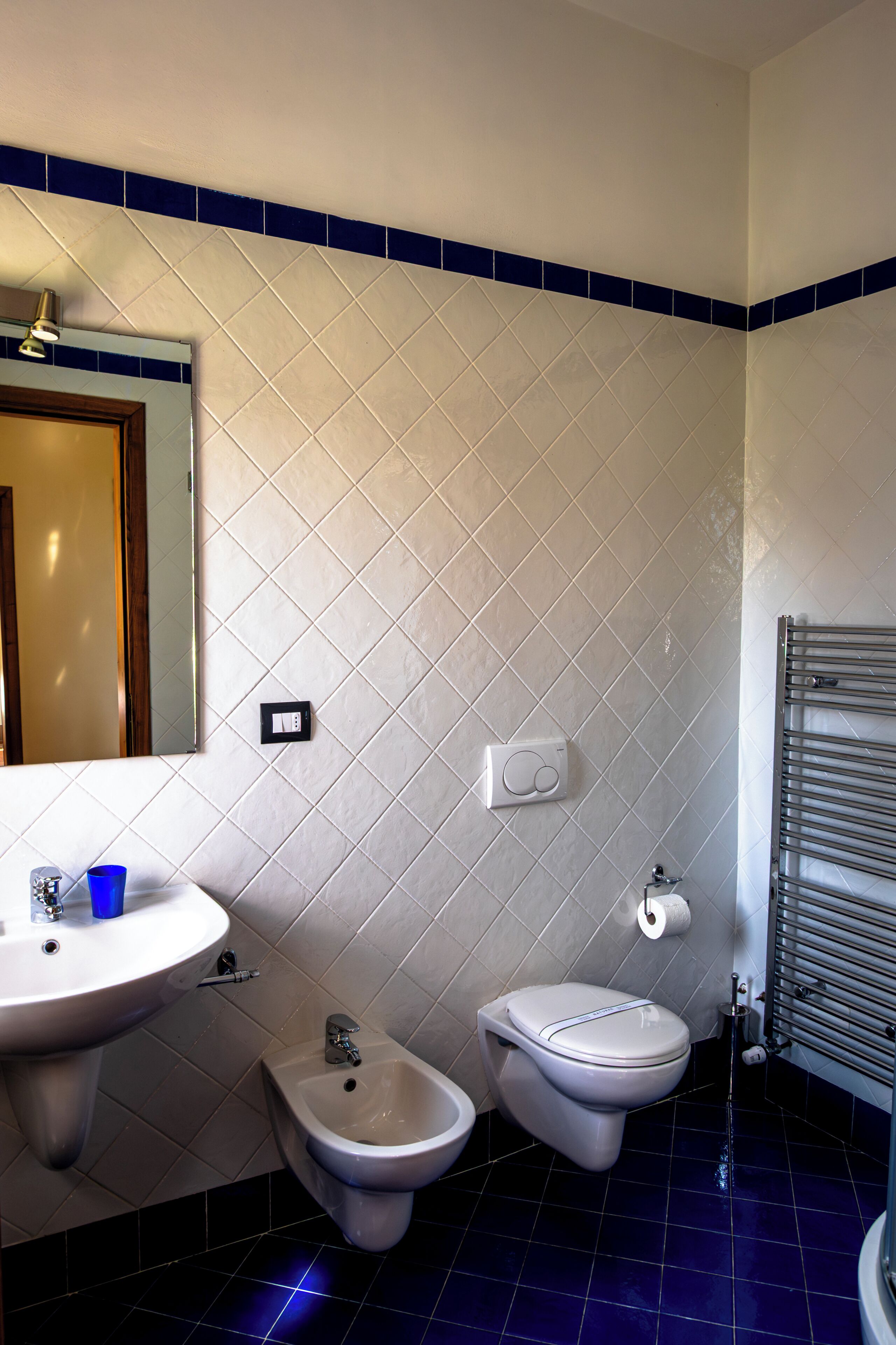 Un baño con lavamanos, bidé, inodoro y un perchero para toallas.