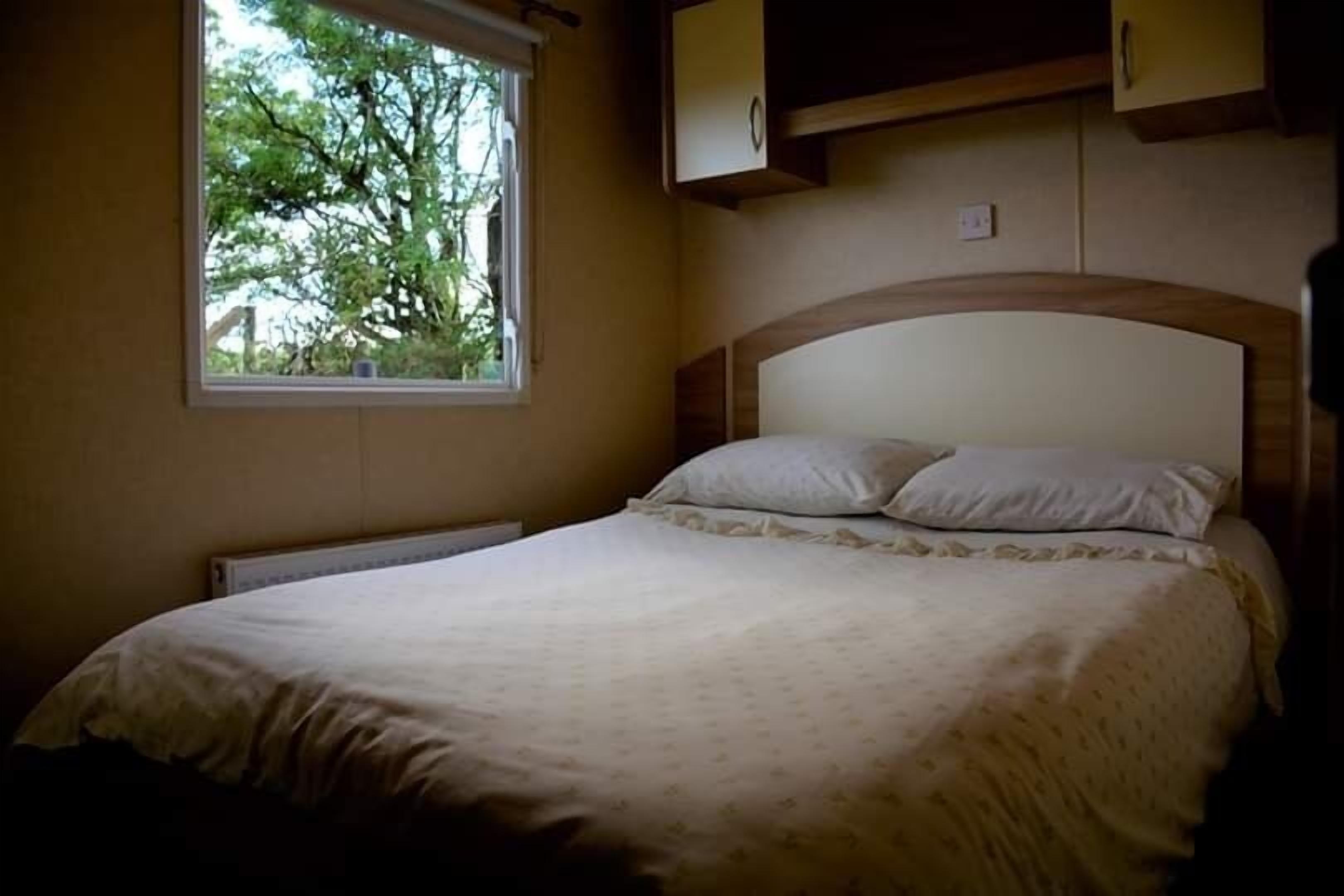A bedroom with a bed, a window, and a wall-mounted cabinet.