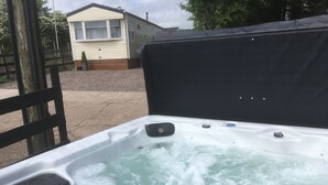 A hot tub with water jets, surrounded by a wooden fence and a house in the background. - Crockgarve (Dungannon)