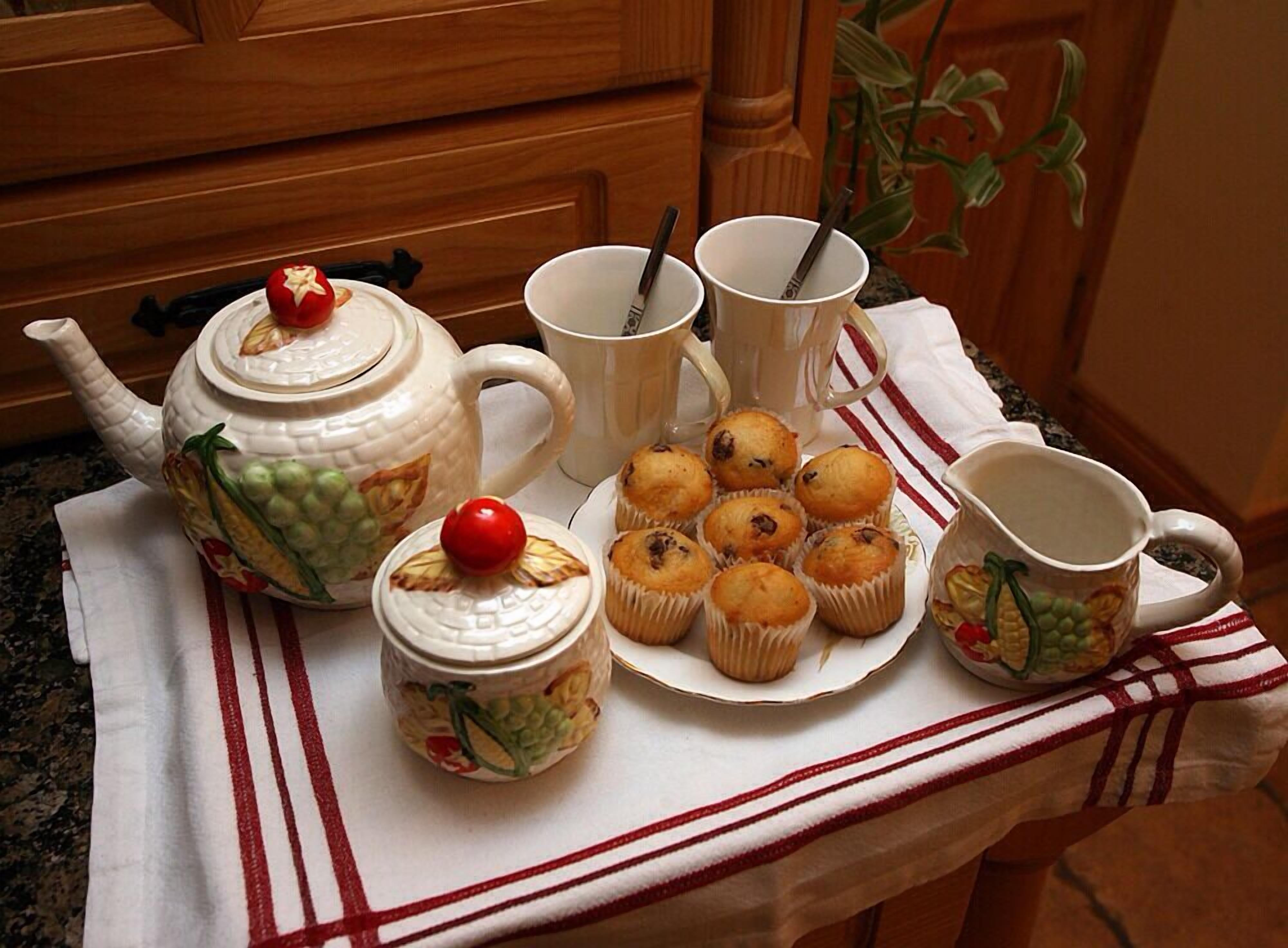Eine Küchenarbeitsplatte mit Teekanne, Tassen und Muffins.