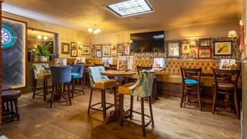 Un interior de restaurante con suelo de madera, asientos de bar y diversas fotografías enmarcadas en las paredes.