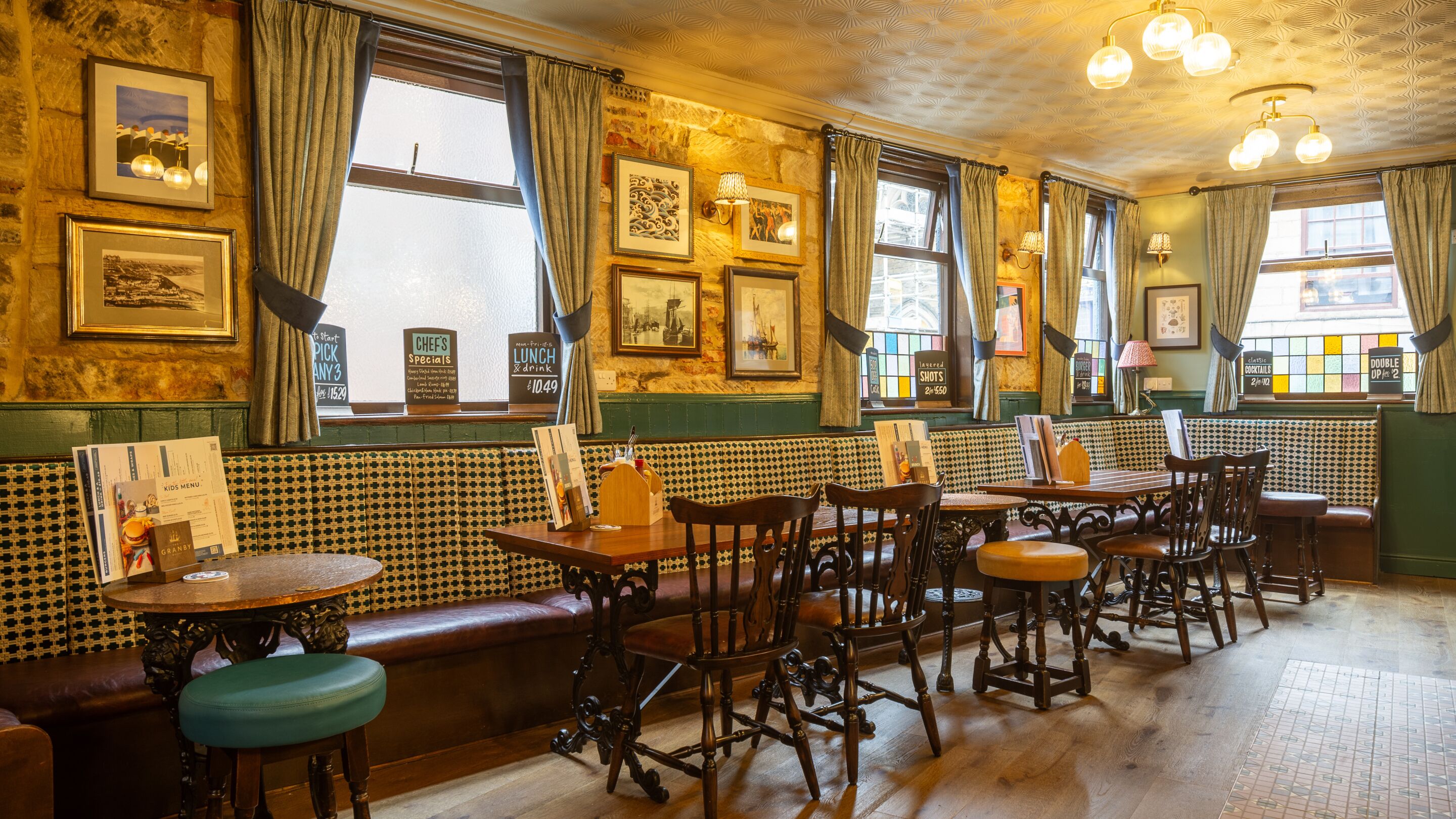 A traditional pub interior with wooden furniture, green walls, and framed pictures.