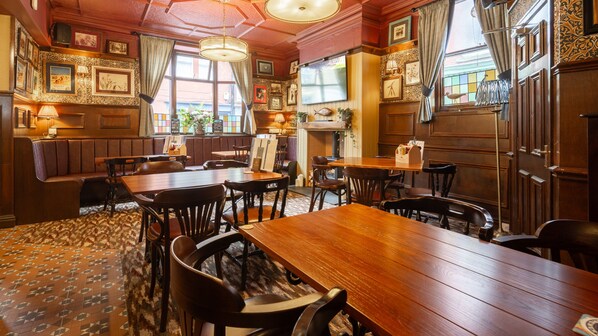 Une auberge traditionnelle avec des meubles en bois, une cheminée et des tableaux encadrés aux murs.