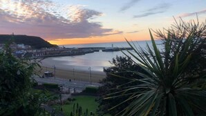 A coastal town at sunset with a bridge, beach, and greenery. - Harcourt Place (Scarborough)
