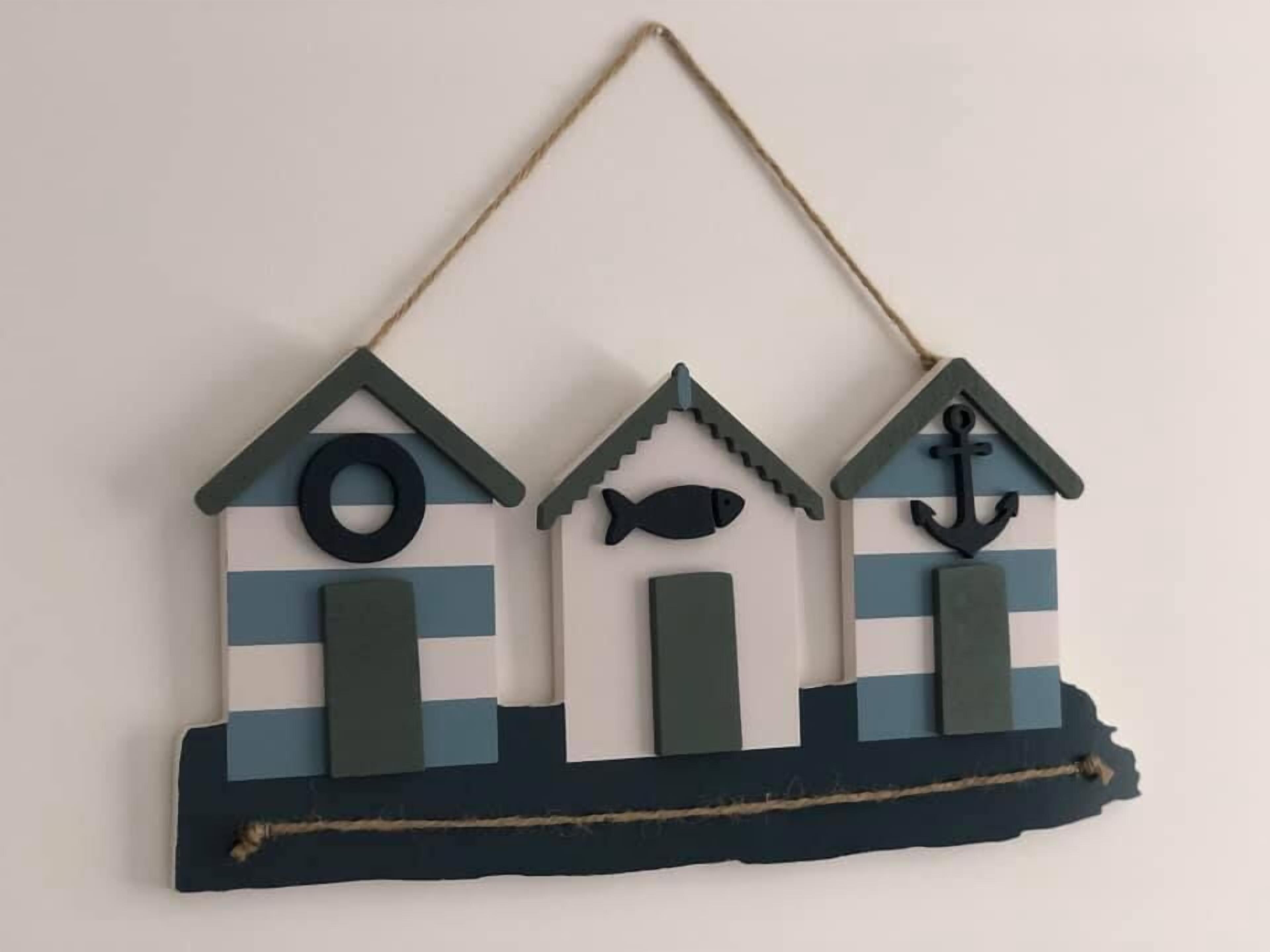 Un tapiz decorativo con tres casas estilizadas, cada una con un símbolo distinto en la fachada.