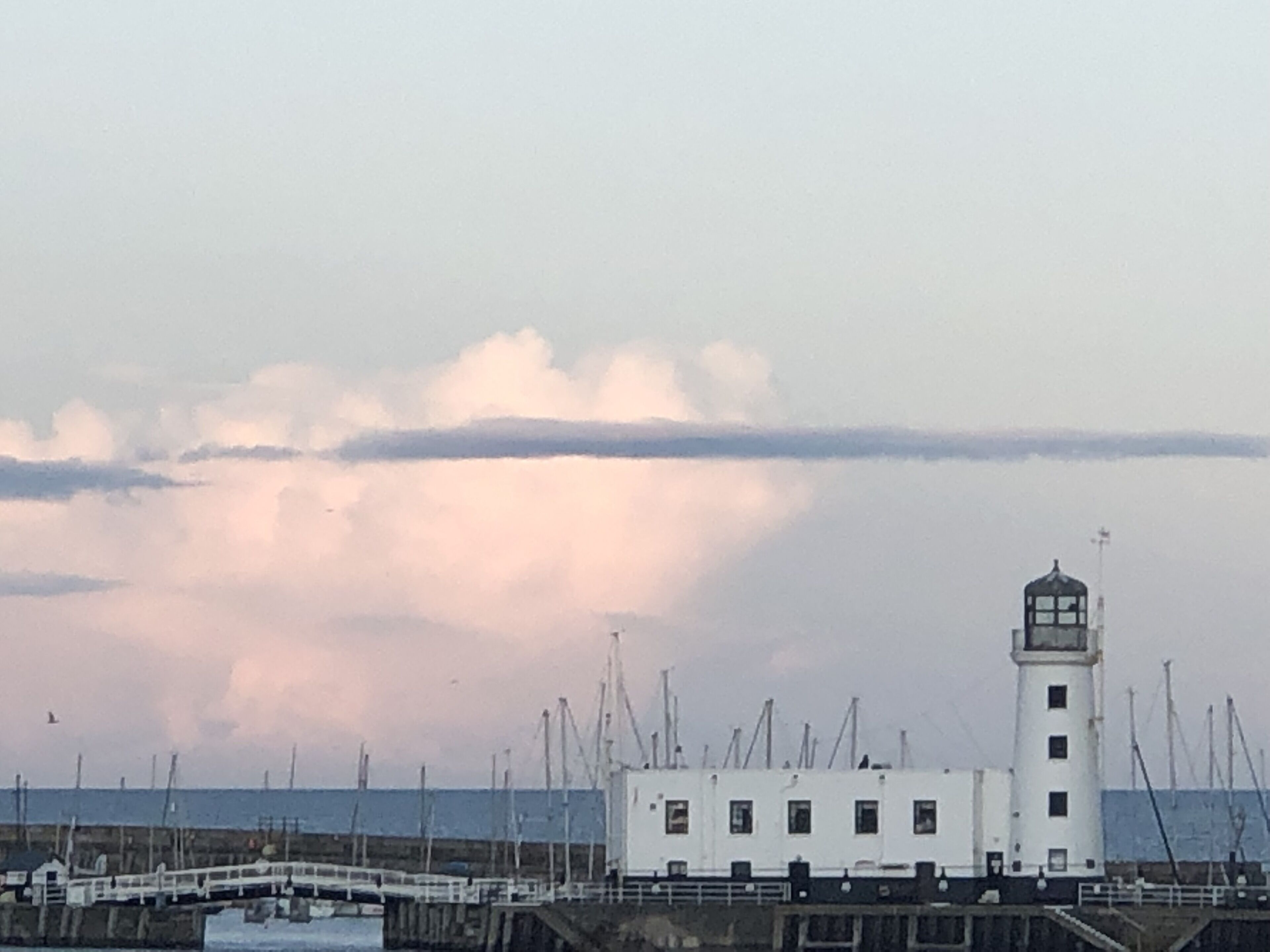 A white lighthouse with a clear sky and clouds in the background.
