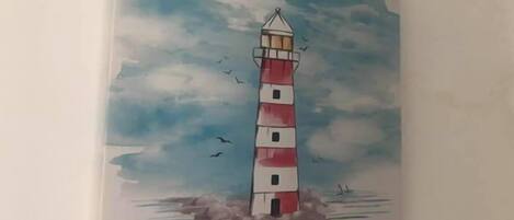 Un faro con una parte superior a rayas rojas y blancas, rodeado de agua y nubes.