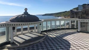 A seaside terrace with a checkered floor, a dome structure, and a view of the ocean and cliffs. - Harcourt Place (Scarborough)