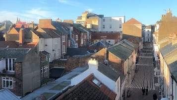 Une rue étroite bordée de bâtiments traditionnels, dont certains présentent des cheminées apparentes et des toits en tuiles.