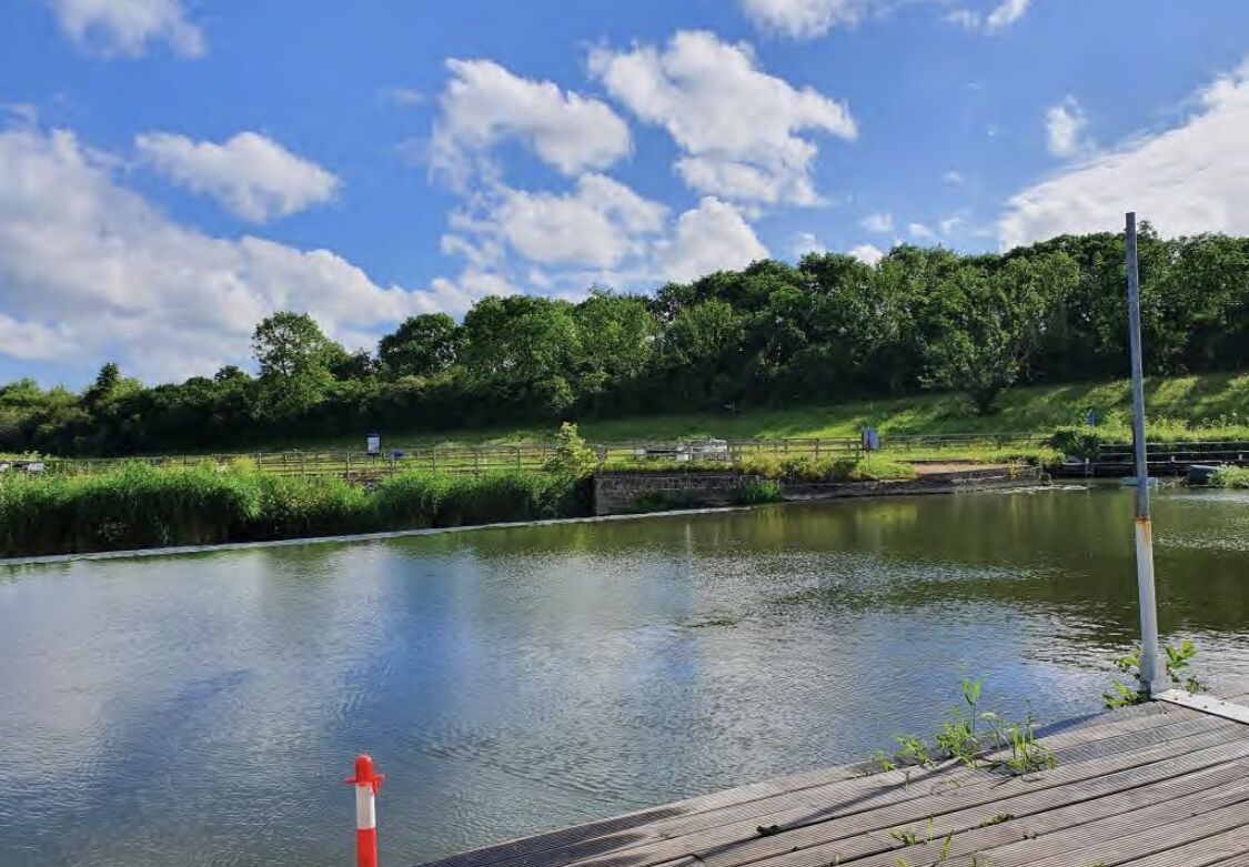 Une rivière paisible avec un quai en bois et une bouée rouge et blanche.