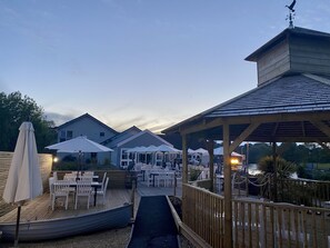 A waterfront restaurant with outdoor seating, covered areas, and a view of the water.