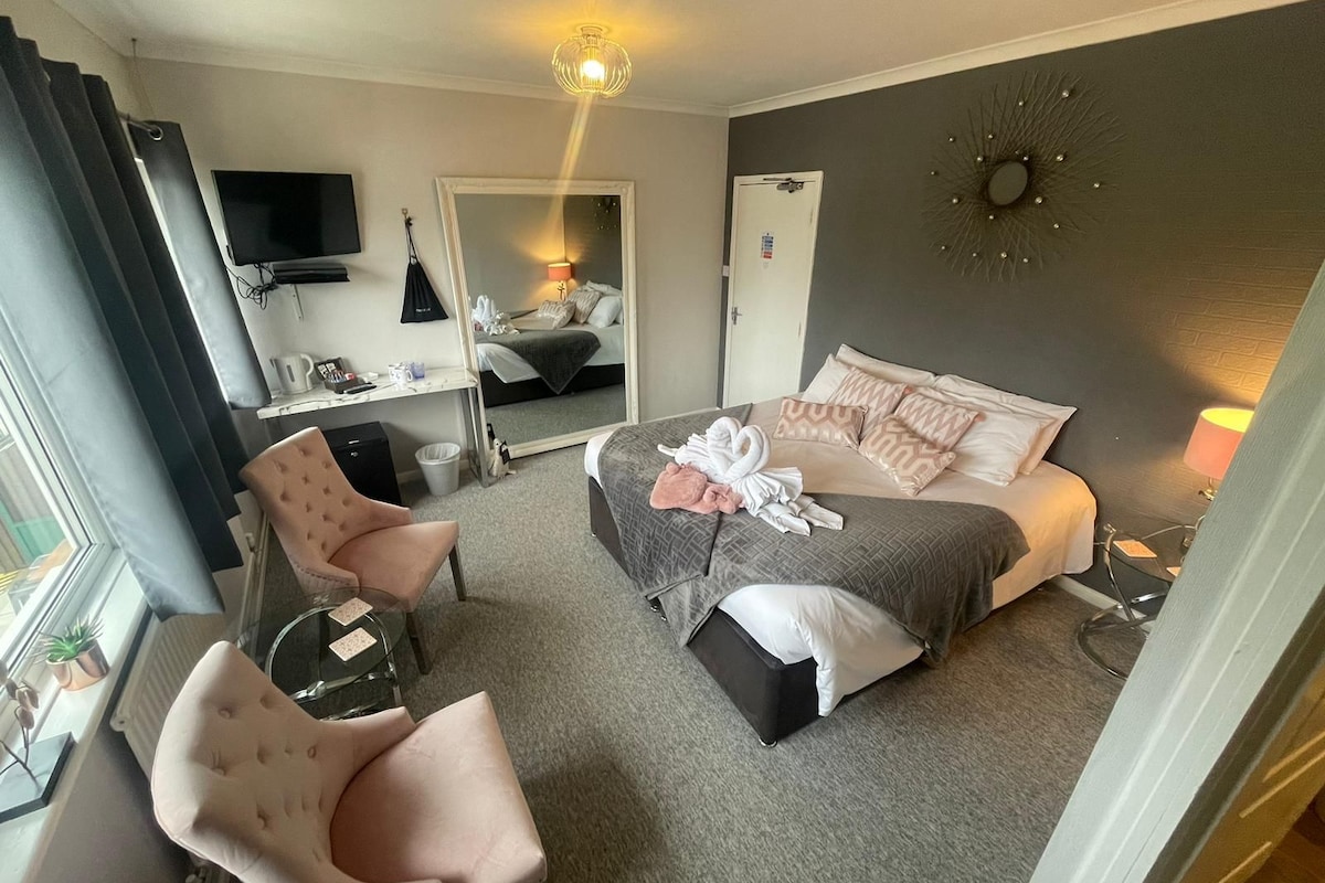 A hotel room with a bed, a desk, a chair, a TV, and a mirror.