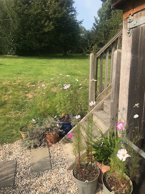 A garden area with a wooden staircase leading to a deck, surrounded by potted plants and flowers.