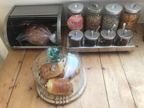 A kitchen counter with a bread display, a breadmaker, and jars of homemade granola and other ingredients. - Rosebank Bed & Breakfast (Etchingham)