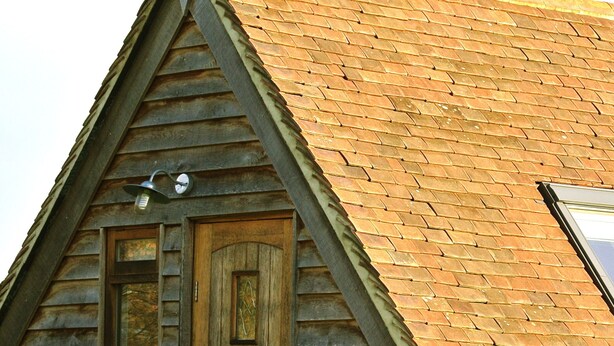 A wooden cabin with a steeply pitched roof, a wooden door, and a small window. - Rosebank Bed & Breakfast (Etchingham)