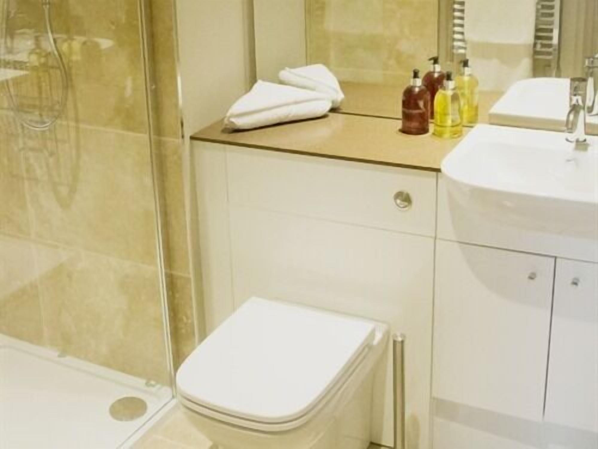 A bathroom with a toilet, a sink, and a shower. There are toiletries on the sink counter.