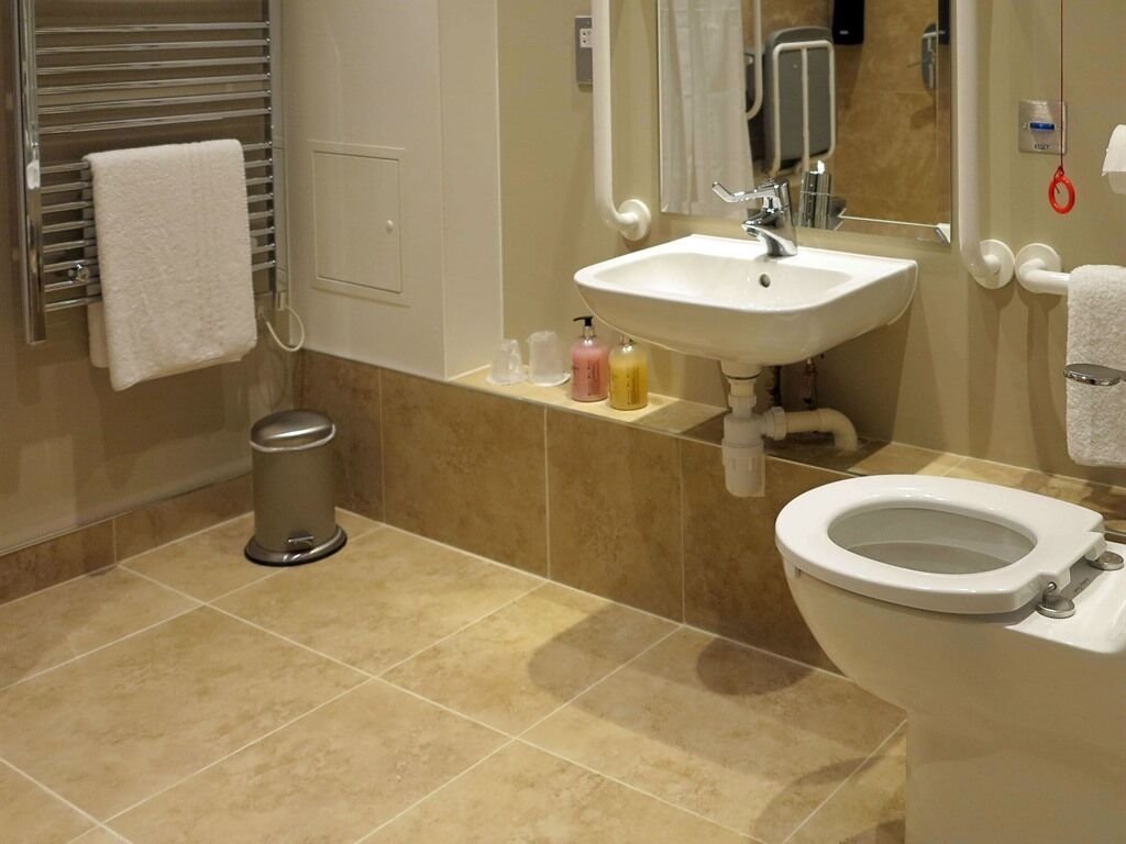 Un baño moderno con lavamanos, inodoro y toallero blancos.