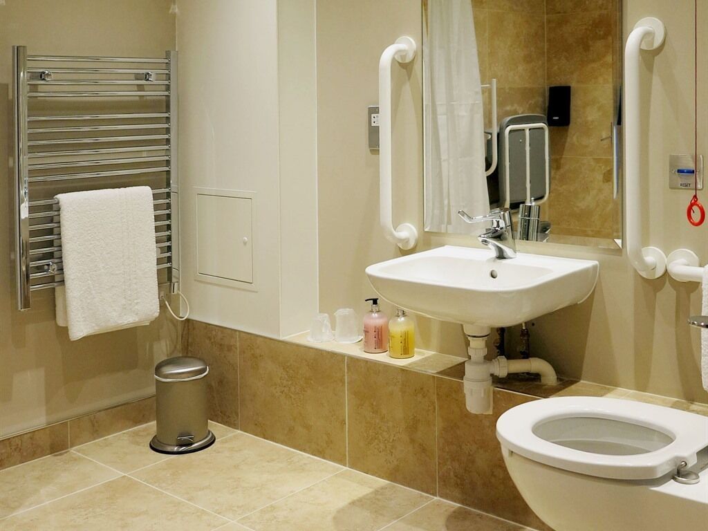 Et moderne badeværelse med en hvid vask, toilet og håndklædestang.