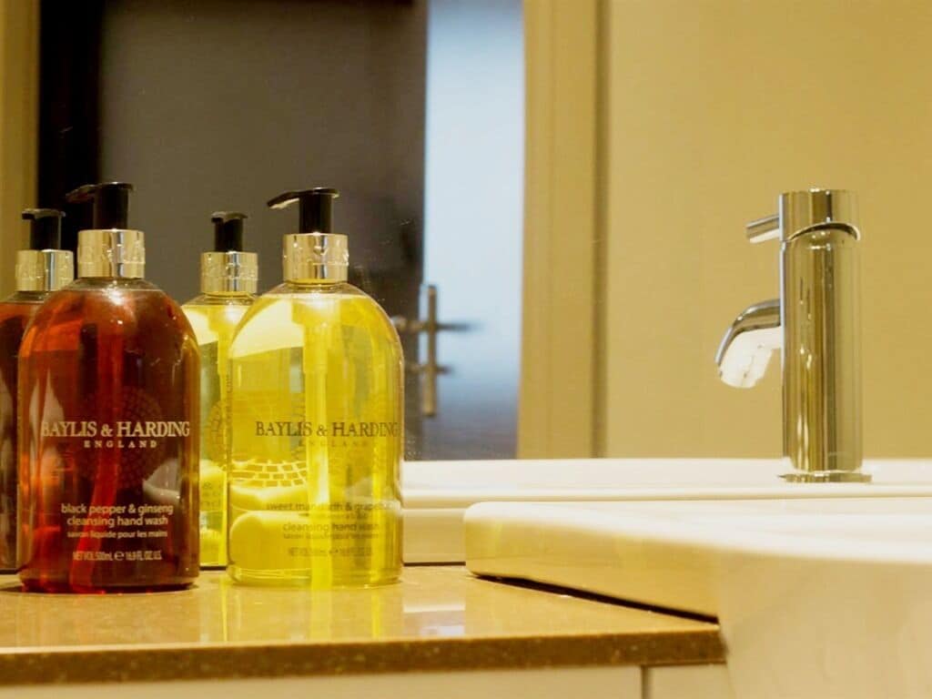 Un meuble-lavabo de salle de bain avec des flacons de savon liquide portant l'inscription « Baylis & Harding » et un robinet moderne.
