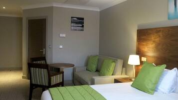 A hotel room with a bed, a desk, a chair, and a small table.