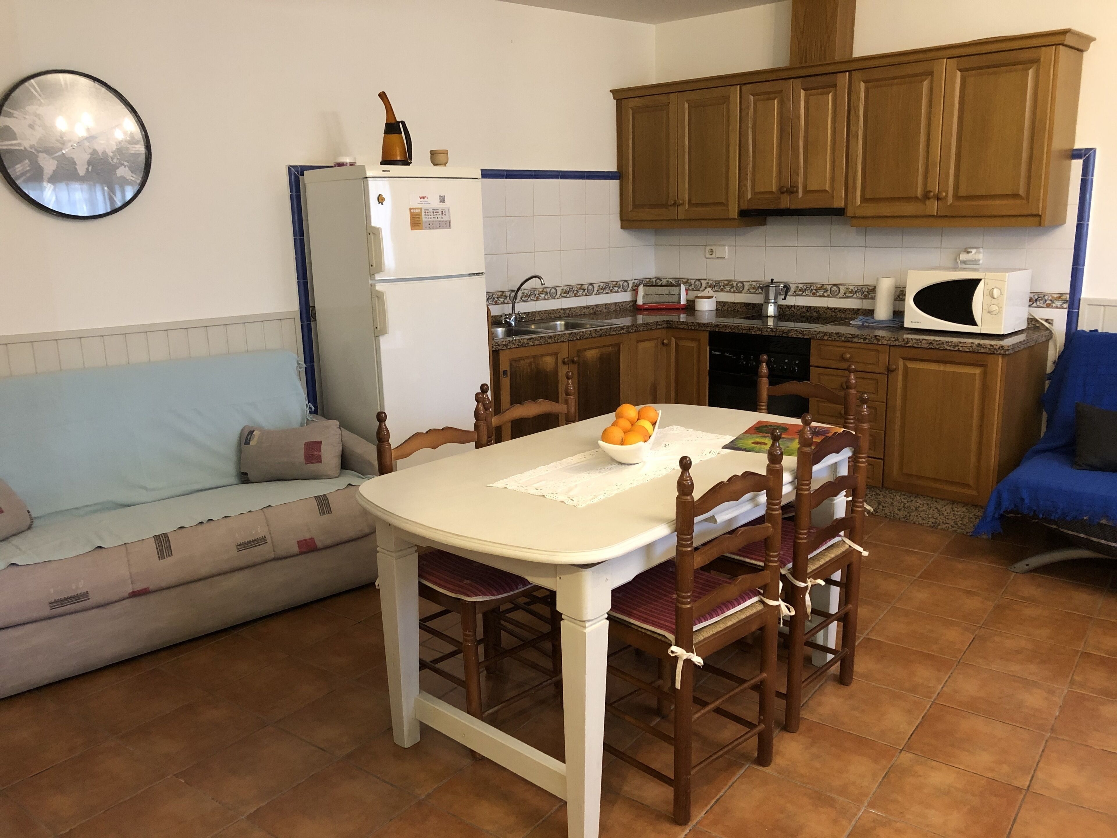 Une cuisine compacte comprenant une table à manger, des chaises, un réfrigérateur, un four à micro-ondes et des armoires en bois.