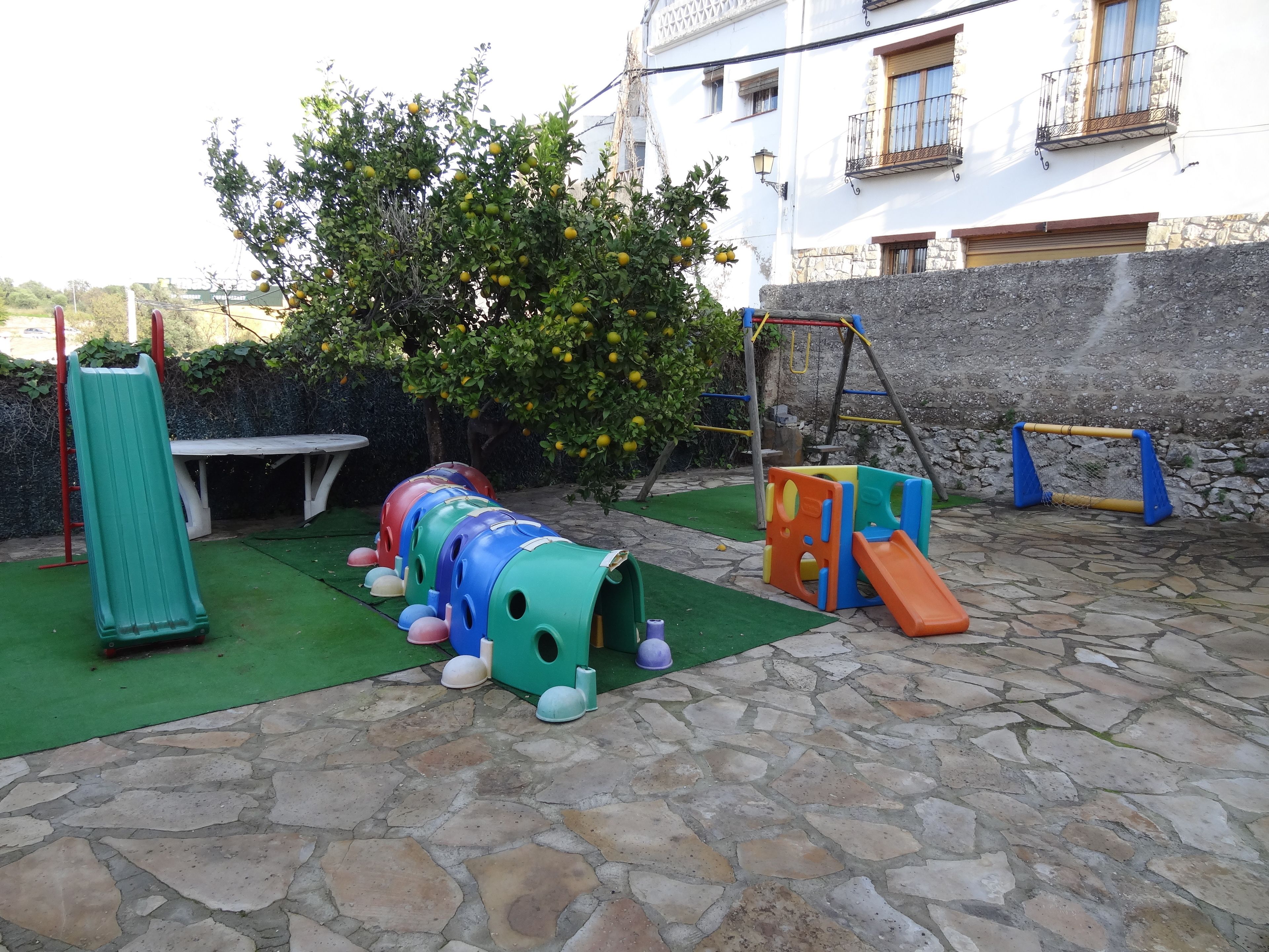 Un área de juegos infantiles con tobogán, estructura para escalar y columpios.