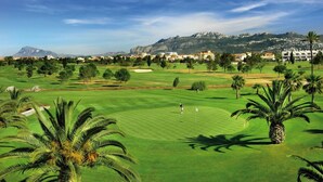 A golf course with a view of a mountain and residential buildings in the background. - La Casa del Carrebaix (Orba)